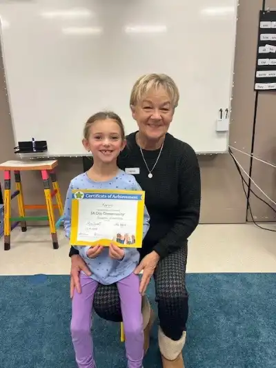Image of a female volunteer with a student holding a certificate
